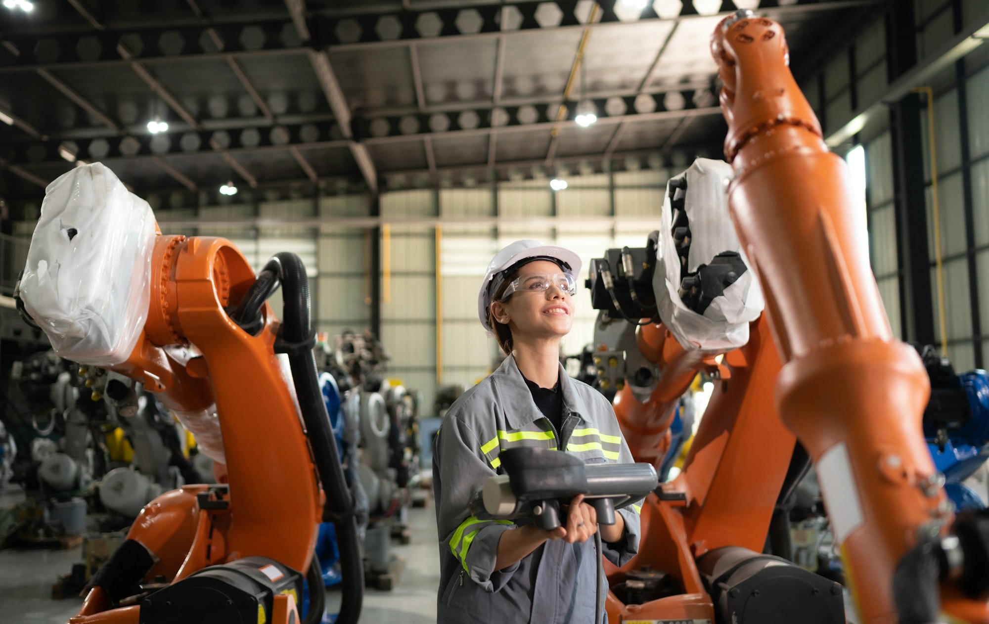 After installing a program on the robotic arm, a female engineer with a robotic arm